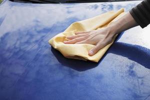 secando à mão o capô de um carro com uma toalha amarela foto