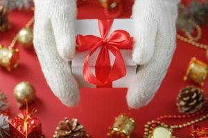caixa de presente branca com um laço vermelho nas luvas. presente de natal ou ano novo. foto