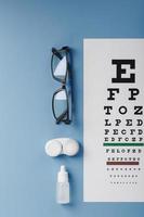 óculos e lentes de acessórios oftálmicos com um gráfico de teste de olho para correção de visão em um fundo azul foto