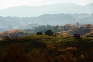 colorida paisagem de outono na aldeia de montanha. manhã de nevoeiro nas montanhas dos cárpatos na romênia. natureza incrível. foto