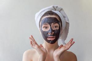 mulher aplicando máscara nutritiva preta no rosto foto