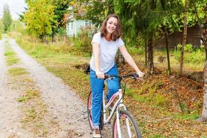 jovem andando de bicicleta no parque da cidade de verão ao ar livre. pessoas ativas. garota hipster relaxa e motociclista. ciclismo para trabalhar no dia de verão. conceito de estilo de vida de bicicleta e ecologia. foto