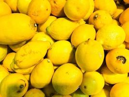 lindo amarelo maduro sul natural vitamina azeda deliciosos limões brilhantes maduros. textura, fundo foto