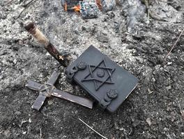 cruz de madeira, estaca e livro de magia negra sobre as cinzas