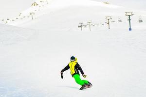 gudauri, geórgia, 2022 - snowboard de menino caucasiano na vista frontal da encosta elegante sozinho sem capacete e luvas em condições frias de inverno na estância de esqui foto