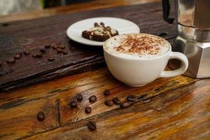 cappuccino quente em copo branco com fundo de madeira, o café é uma bebida popular em todo o mundo. foto