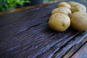 dieta de batata crua. batatas frescas no piso de madeira. espaço para mensagens. batatas cruas que podem ser usadas em muitos pratos. foto