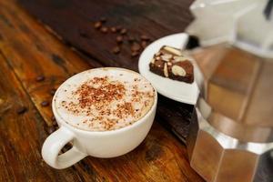 cappuccino quente em copo branco com fundo de madeira, o café é uma bebida popular em todo o mundo. foto