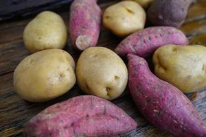 dieta de batata crua. batatas frescas no piso de madeira. espaço para mensagens. batatas cruas que podem ser usadas em muitos pratos. foto