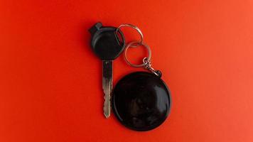 chave de motocicleta preta com chaveiro redondo preto sobre fundo vermelho. maquete de chaveiro para design foto