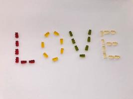 palavra amor feito de marmelada. letras de ursinhos de goma nas cores verde, branco, amarelo e verde. sobremesa deliciosa de alto teor calórico. letras criativas com letras comestíveis foto