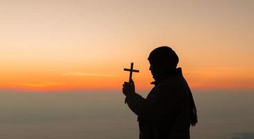 conceito pessoa cristã adorar ou orar a Deus. silhueta de homem cristão com amor, fé, devoção a Deus com céu nascer do sol background.male adoração deus para paz, vitória, sucesso com esperança. religião foto