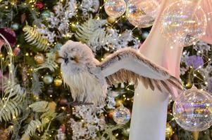 decorações de natal para o centro comercial. decoração de vitrine. coruja pendurada em um galho de abeto. pássaros pendem das árvores. bolas brilhantes transparentes na árvore de natal foto