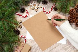 mão de famale escrevendo uma carta de natal em fundo de madeira foto