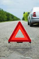 carro com problemas e um triângulo vermelho para avisar outros usuários da estrada foto