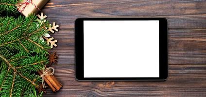 tablet digital simulado com decorações rústicas de fundo de madeira de natal para apresentação de aplicativos. banner de vista superior com espaço de cópia foto