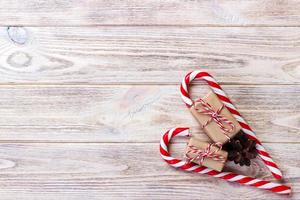 bastões de doces e presente de natal em fundo de madeira marrom foto