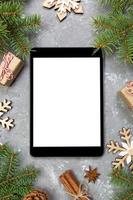 tablet digital simulado com decorações rústicas de fundo de cimento cinza de natal para apresentação de aplicativos. vista superior com espaço de cópia foto