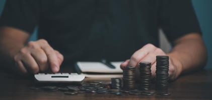 mão de homem segurando a moeda de dinheiro na mesa de madeira, economizando dinheiro riqueza e conceito financeiro, negócios, finanças, investimento, planejamento financeiro. foto