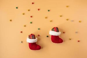 meia de crochê artesanal e caixa de presente em fundo laranja pastel. feliz natal e feliz ano novo conceito. foto