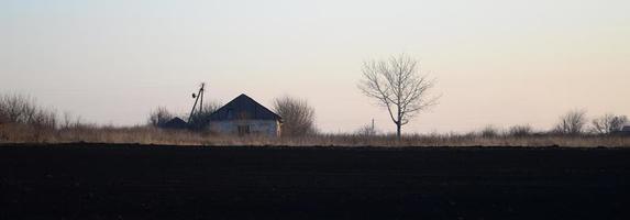 amanhecer na aldeia. uma foto minimalista com uma linha do horizonte na qual há um prédio de apartamentos e uma árvore