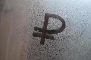 símbolo do rublo russo é escrito com um dedo na superfície do vidro embaçado foto