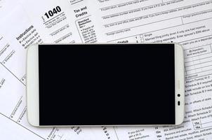 o smartphone encontra-se no formulário fiscal 1040 e w-2. smartphone de tela preta limpa para colocação de texto foto