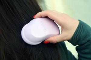 kharkov, ucrânia - 3 de maio de 2021, jovem segura a escova de cabelo rosa emaranhada. tangle teezer é um fabricante britânico de escovas de cabelo para desembaraçar foto