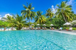 paisagem de turismo ao ar livre. luxuoso resort de praia com piscina e cadeiras de praia ou espreguiçadeiras guarda-sóis com palmeiras e céu azul, horizonte do mar. ilha de verão relaxe viagens e férias idílicas foto