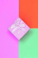pequena caixa de presente rosa encontra-se no fundo de textura do papel de cores turquesa, vermelho e rosa pastel de moda foto