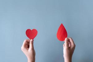doação de sangue ou conceito de cirurgia. humano segurando sinal de sangue e uma forma de coração vermelho.