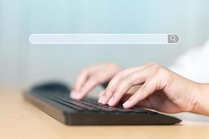 close-up da mão humana digitando no teclado do computador com o navegador do mecanismo de pesquisa foto