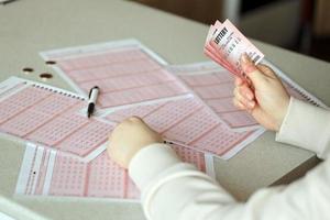 preenchimento de um bilhete de loteria. uma jovem segura o bilhete de loteria com linha completa de números no fundo de folhas em branco de loteria. foto