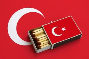 a bandeira da turquia é mostrada em uma caixa de fósforos aberta, que está cheia de fósforos e fica em uma bandeira grande foto