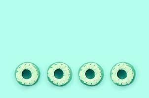 muitos pequenos donuts de plástico encontram-se em um fundo colorido pastel. padrão mínimo de postura plana. vista do topo foto