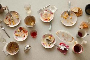 pratos sujos vazios com colheres e garfos na mesa após a refeição. conceito de final de banquete. pratos sujos foto