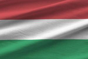 bandeira da Hungria com grandes dobras acenando de perto sob a luz do estúdio dentro de casa. os símbolos oficiais e cores no banner foto