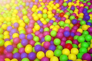 muitas bolas de plástico coloridas em uma piscina infantil em um playground. padrão de close-up foto