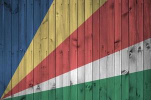 bandeira de seychelles retratada em cores brilhantes de tinta na parede de madeira velha. banner texturizado em fundo áspero foto