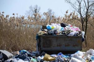 a lata de lixo é embalada com lixo e resíduos. remoção prematura de lixo em áreas povoadas foto