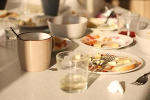pratos sujos vazios com colheres e garfos na mesa após a refeição. conceito de final de banquete. pratos sujos foto