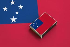 bandeira de samoa é retratada em uma caixa de fósforos que fica em uma grande bandeira foto