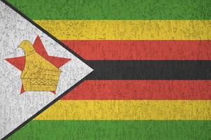 bandeira do zimbabwe retratada em cores de tinta brilhante na parede de reboco em relevo antigo. banner texturizado em fundo áspero foto