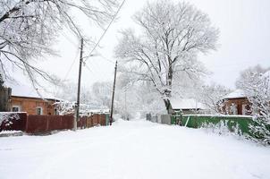 uma paisagem rústica de inverno com algumas casas antigas e uma estrada larga coberta por uma espessa camada de neve foto