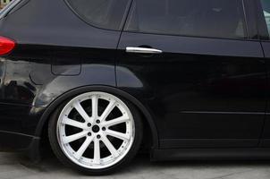 vista lateral de um carro preto brilhante com rodas brancas foto