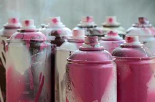 um monte de latas de aerossol sujas e usadas de tinta rosa brilhante. fotografia macro com profundidade de campo rasa. foco seletivo no bico de pulverização foto