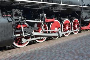 rodas da velha locomotiva a vapor preta dos tempos soviéticos. o lado da locomotiva com elementos da tecnologia rotativa de trens antigos foto