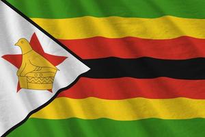 bandeira do zimbabwe com grandes dobras acenando de perto sob a luz do estúdio dentro de casa. os símbolos oficiais e cores no banner foto