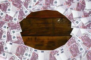 muitas denominações roxas no valor de 500 euros estão em uma superfície de madeira com um bloco vazio no meio da imagem. copie o espaço para o texto foto