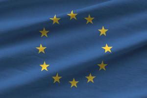 bandeira da união europeia com grandes dobras acenando de perto sob a luz do estúdio dentro de casa. os símbolos oficiais e cores no banner foto